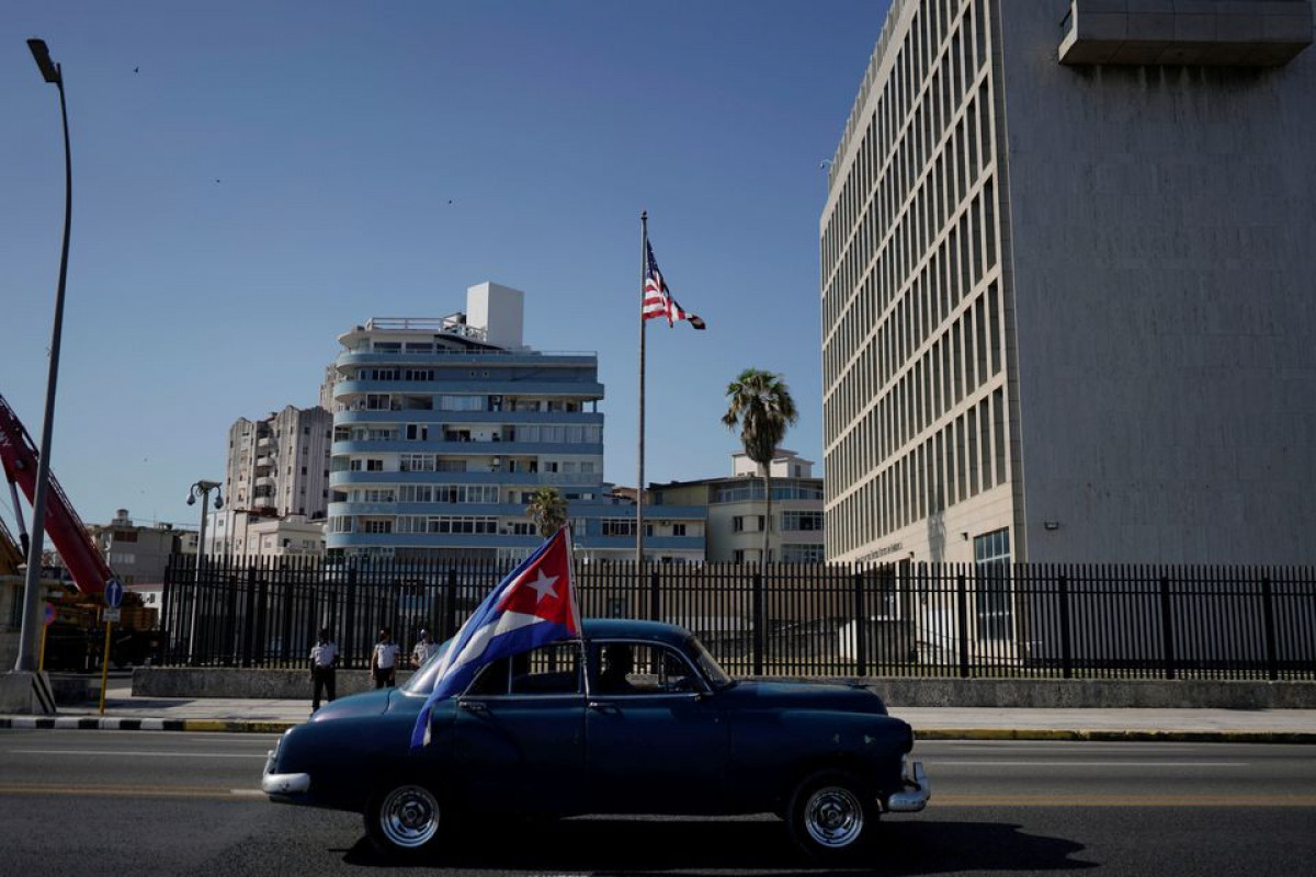 A vintage car passes by the U.S. Embassy carrying a Cuban flag during a motorcade in protest against the trade embargo on Cuba by the U.S. in Havana, Cuba, March 28, 2021.