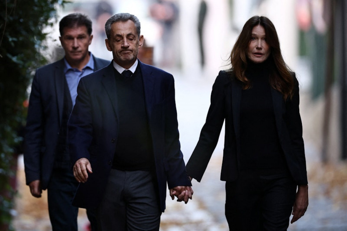 Former French President Nicolas Sarkozy leaves his house with his wife Carla Bruni-Sarkozy on the day of his incarceration